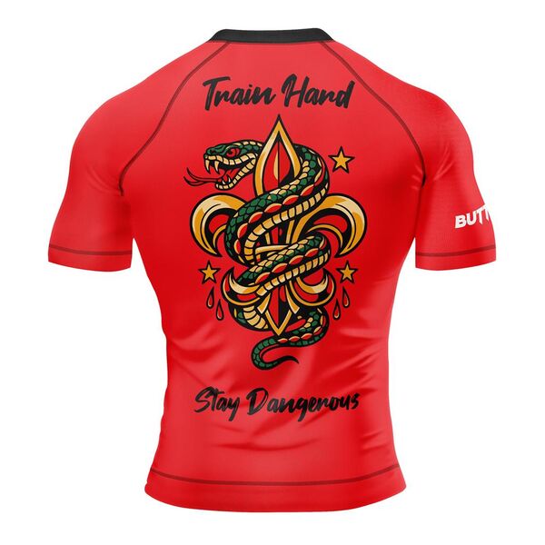 Back of a red rash guard with a snake around a fleur-de-lis between Train Hard and Stay Dangerous